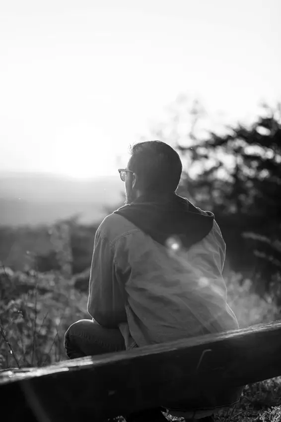 Man sitting on a bench looking over scenic view.